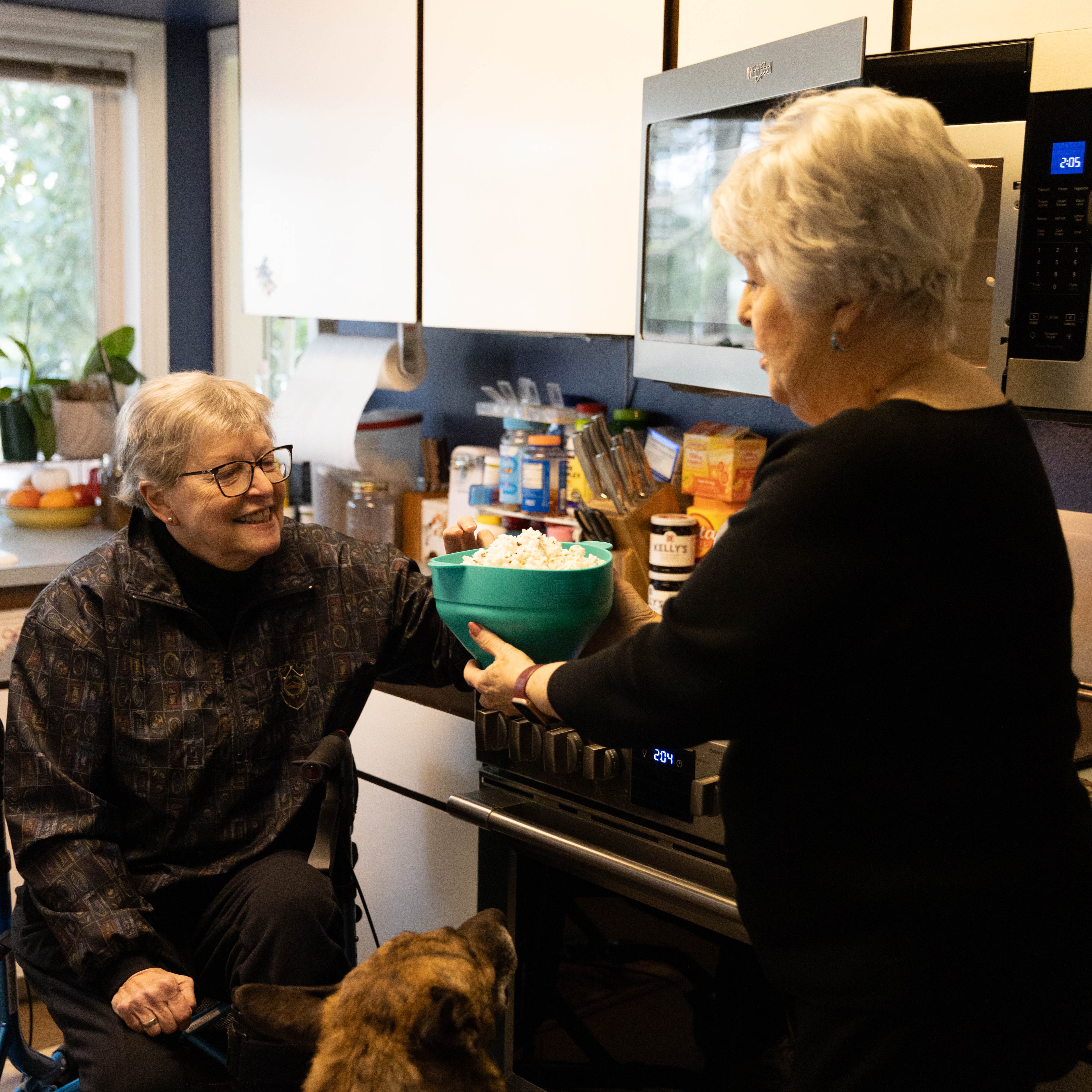 A caregiver hands popcorn to a person living with ALS.