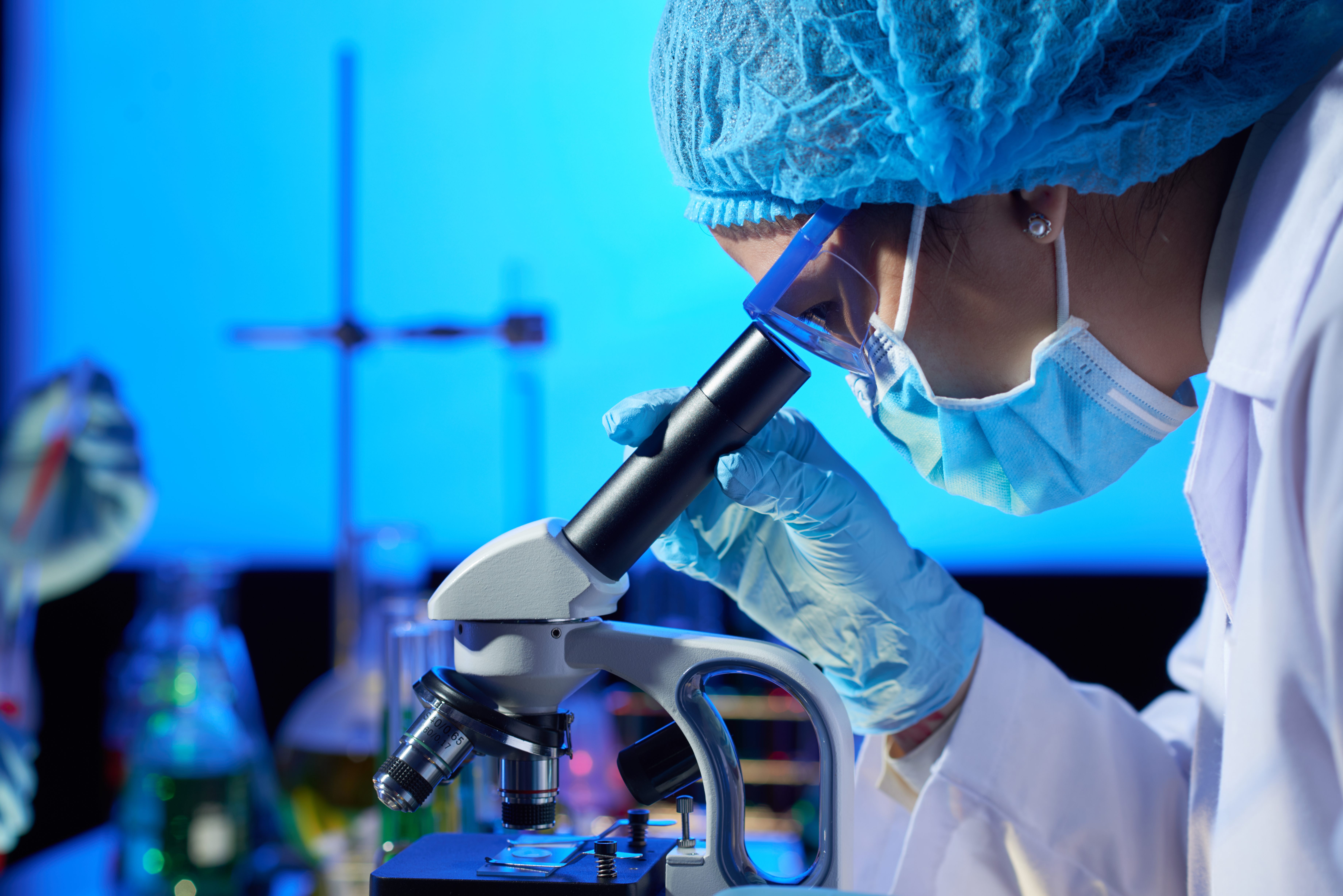 Researcher examining a sample with a microscope.